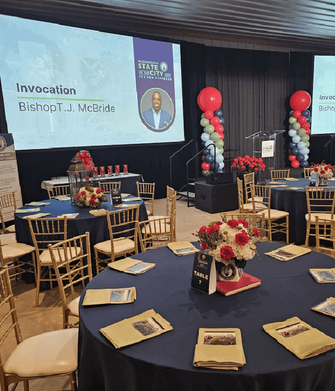 Conference room with decorated tables and presentation screens for Angela J. White Consulting event.
