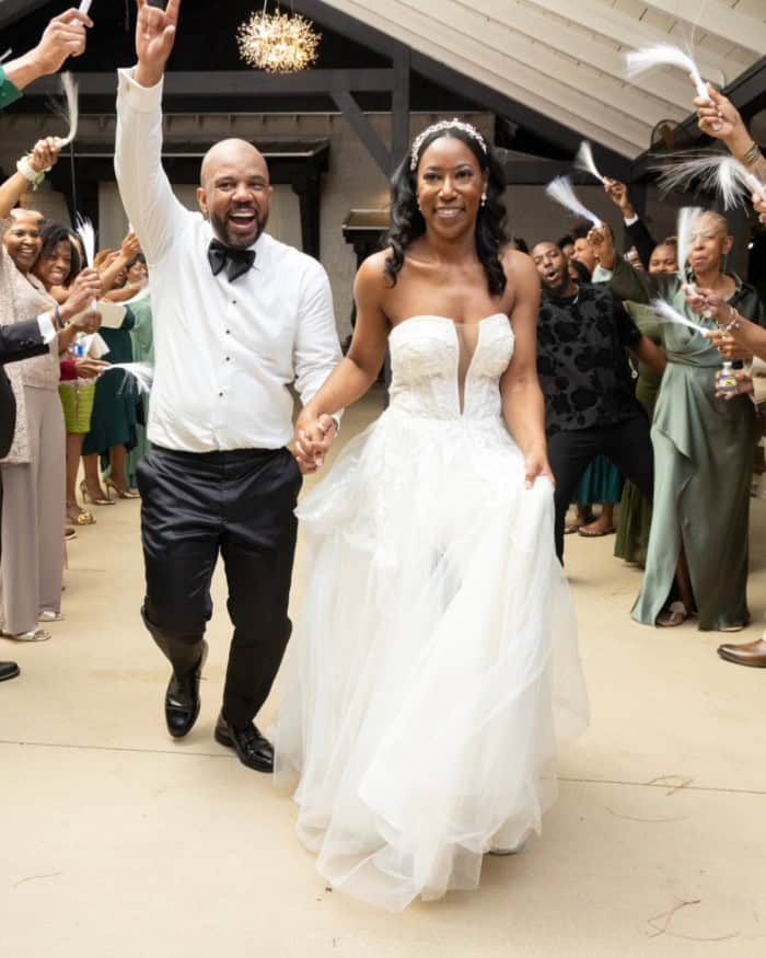 Happy bride and groom celebrating wedding with guests and feathers.