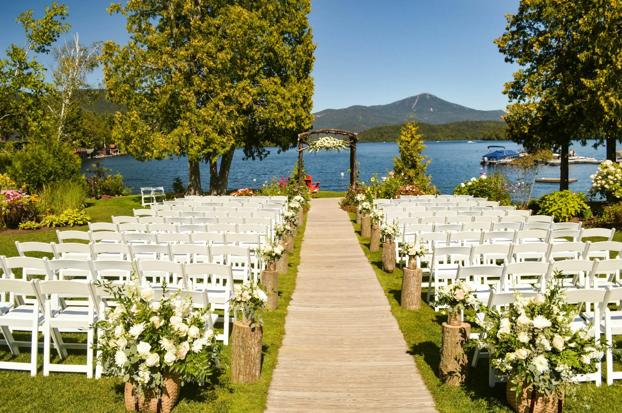 Beautiful outdoor wedding setup with chairs, flowers, and lake view.