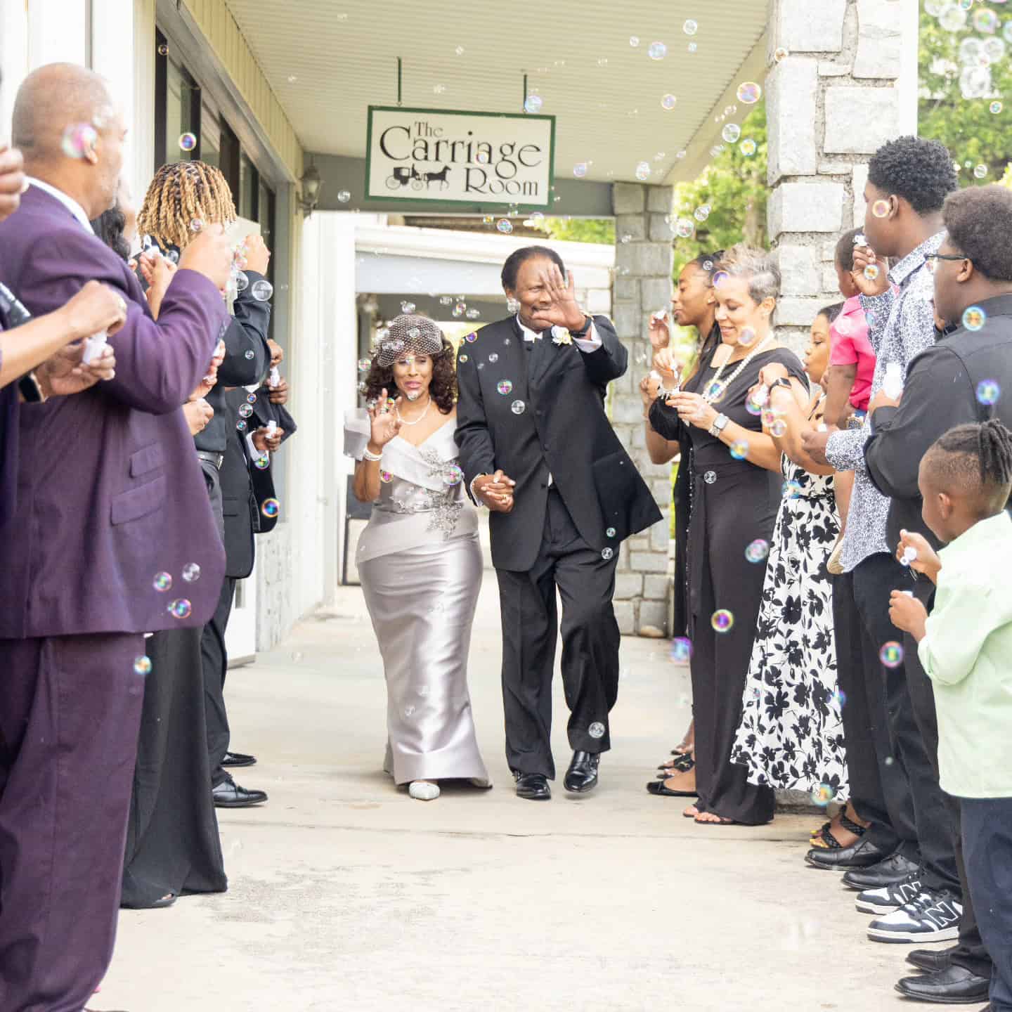People celebrating outside The Carriage Room with bubbles and smiles.