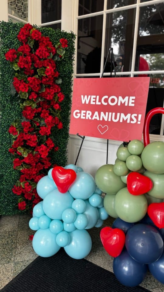 Colorful balloon arrangement with a Geranium-themed welcome sign.