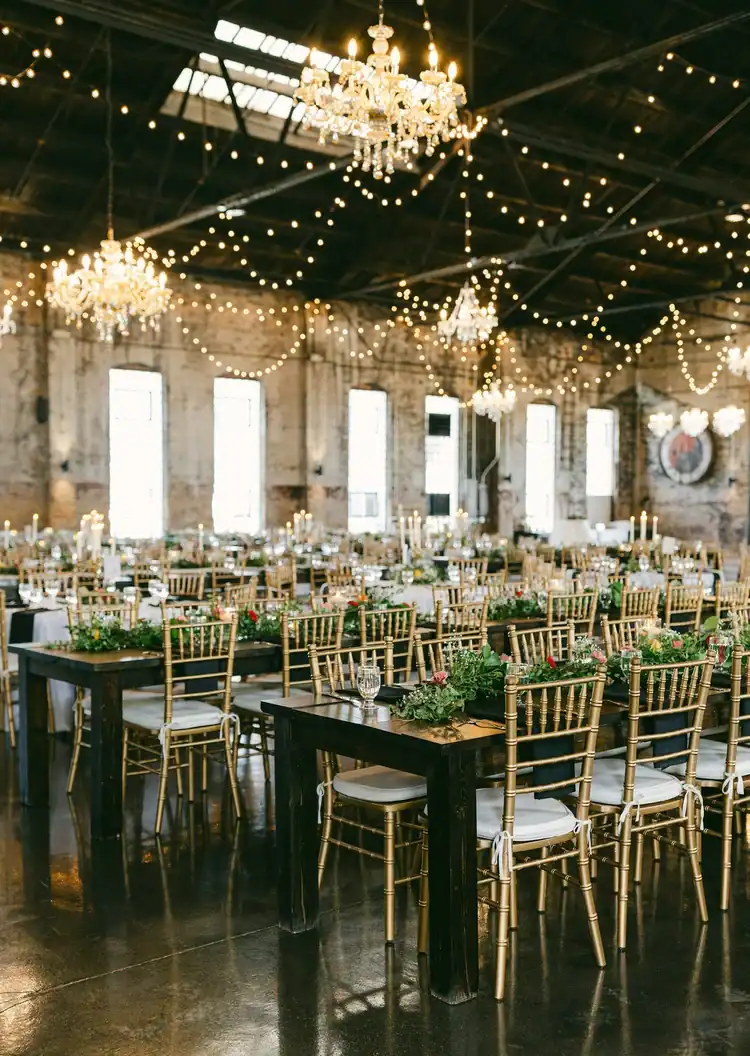 Beautifully decorated event space with chandeliers and string lights for weddings or parties.