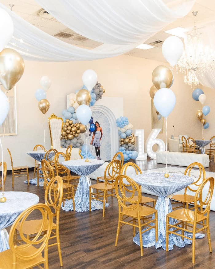Decorated event space with balloons, gold accents, and elegant table settings.