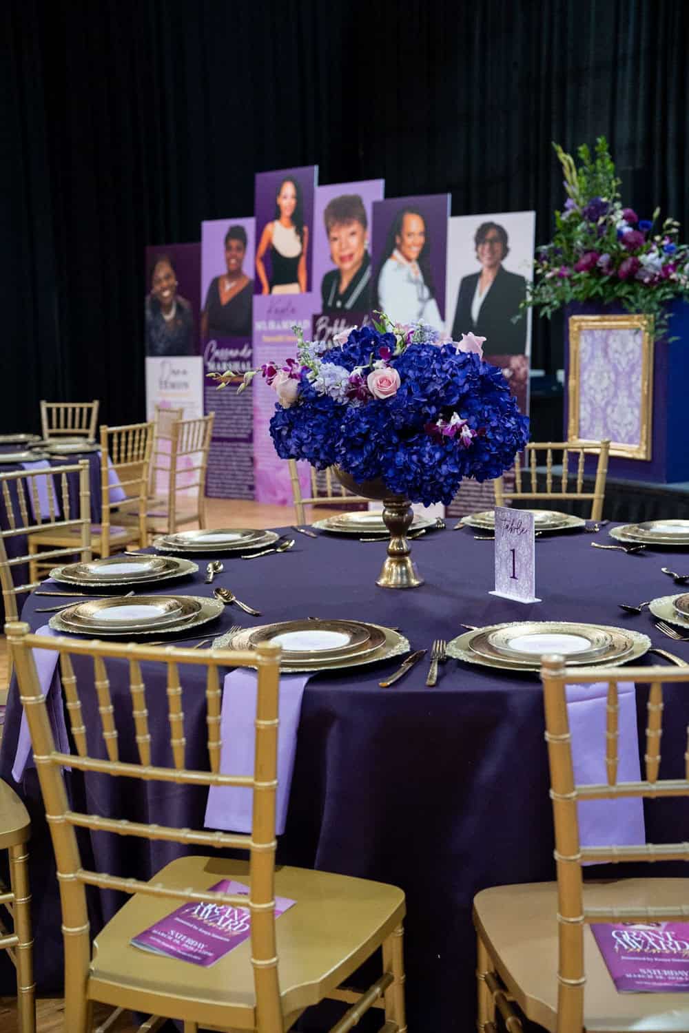 Decorated event table with purple flowers and portraits for Angela J. White Consulting.