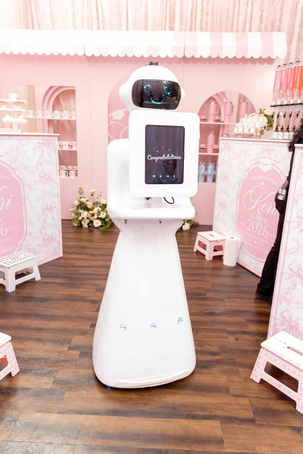 Friendly service robot at Angela J. White Consulting event in pink decor.