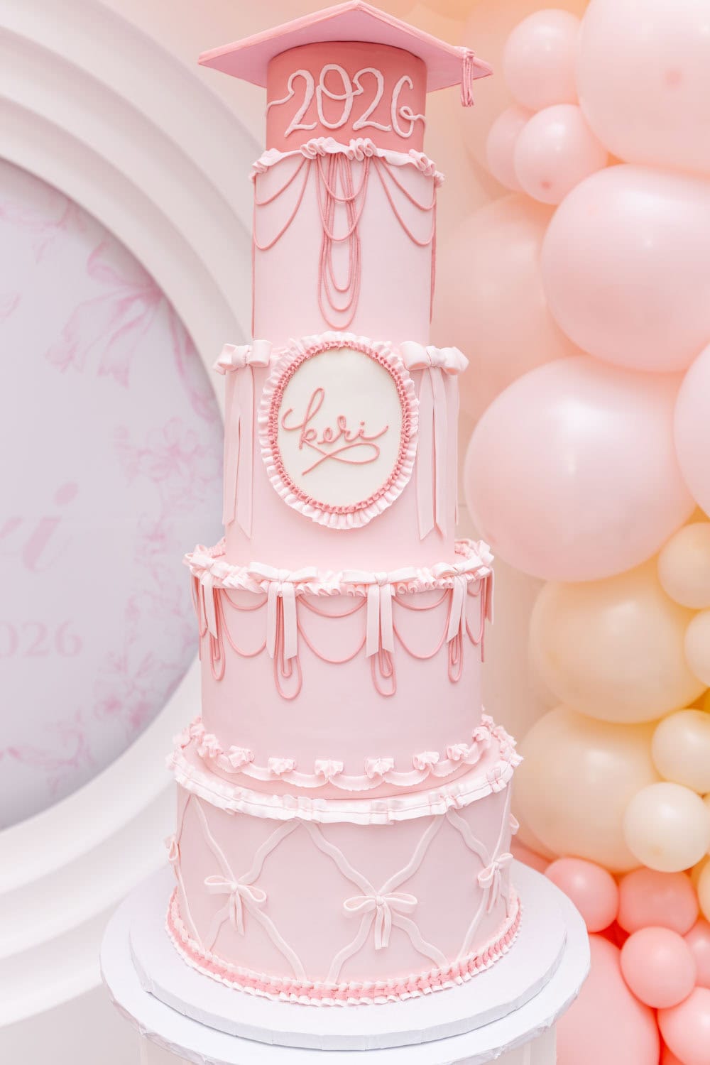 Pink graduation cake with 2026 topper and bow decorations for celebration.