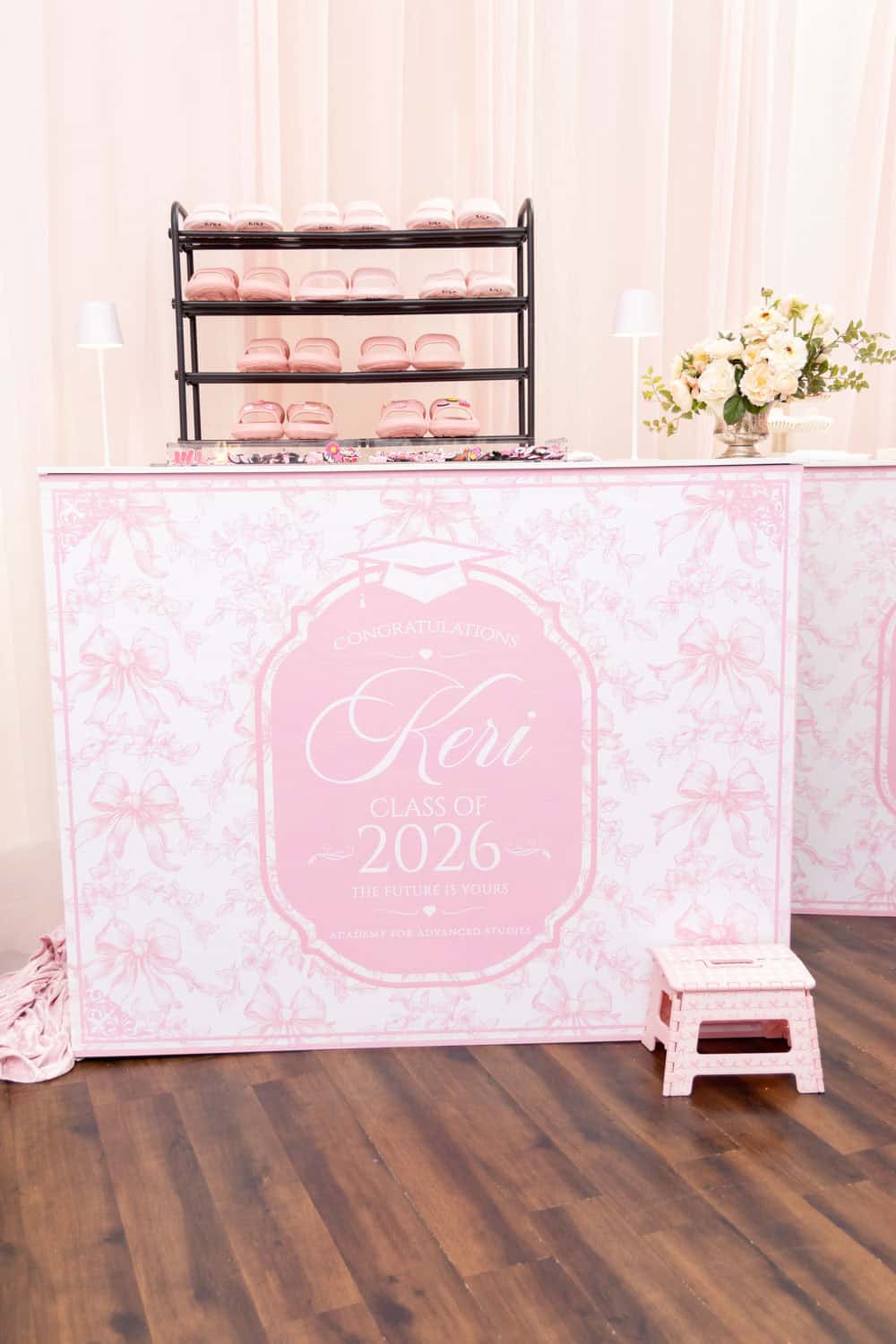 Pink graduation celebration table with floral decor and seating arrangement.