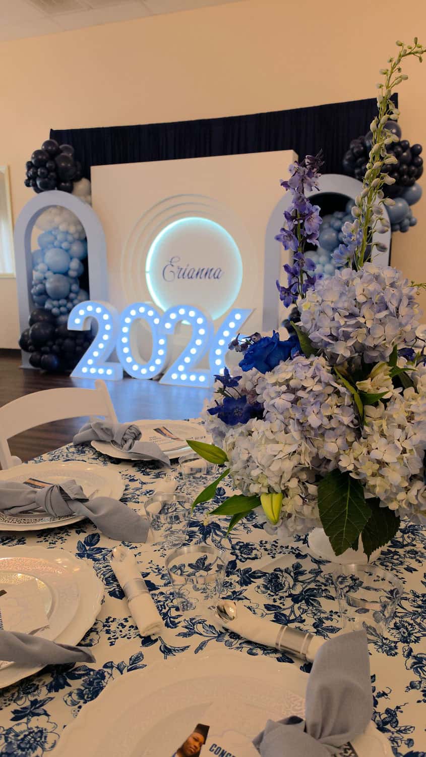 Decorative event setup with floral arrangements and illuminated 2024 sign.