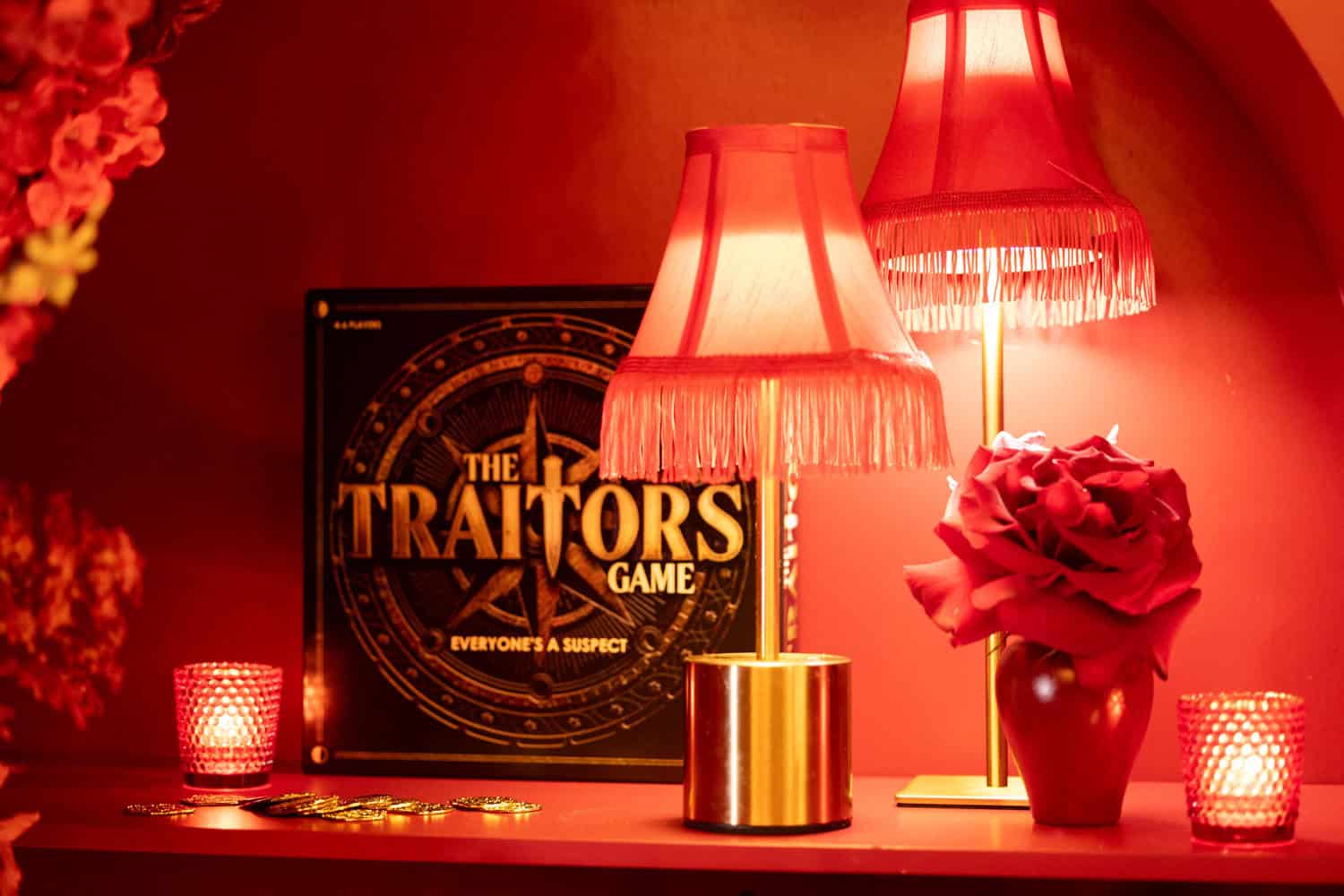 Decorative game setup with lamps, flowers, and game box for The Traitors.