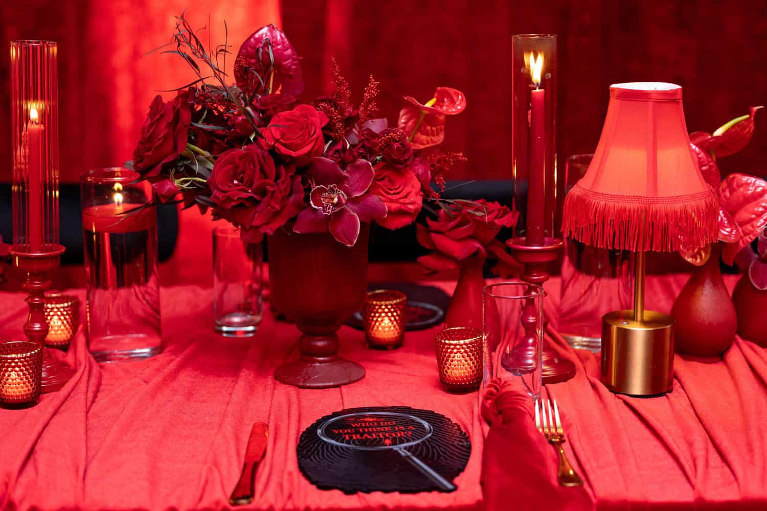 Red-themed table setting with flowers, candles, and elegant decor.