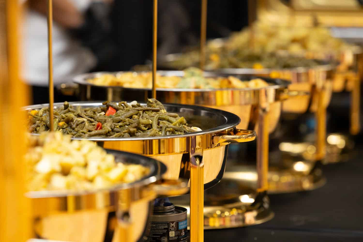 Assorted hot dishes served in gold chafing dishes at a buffet.