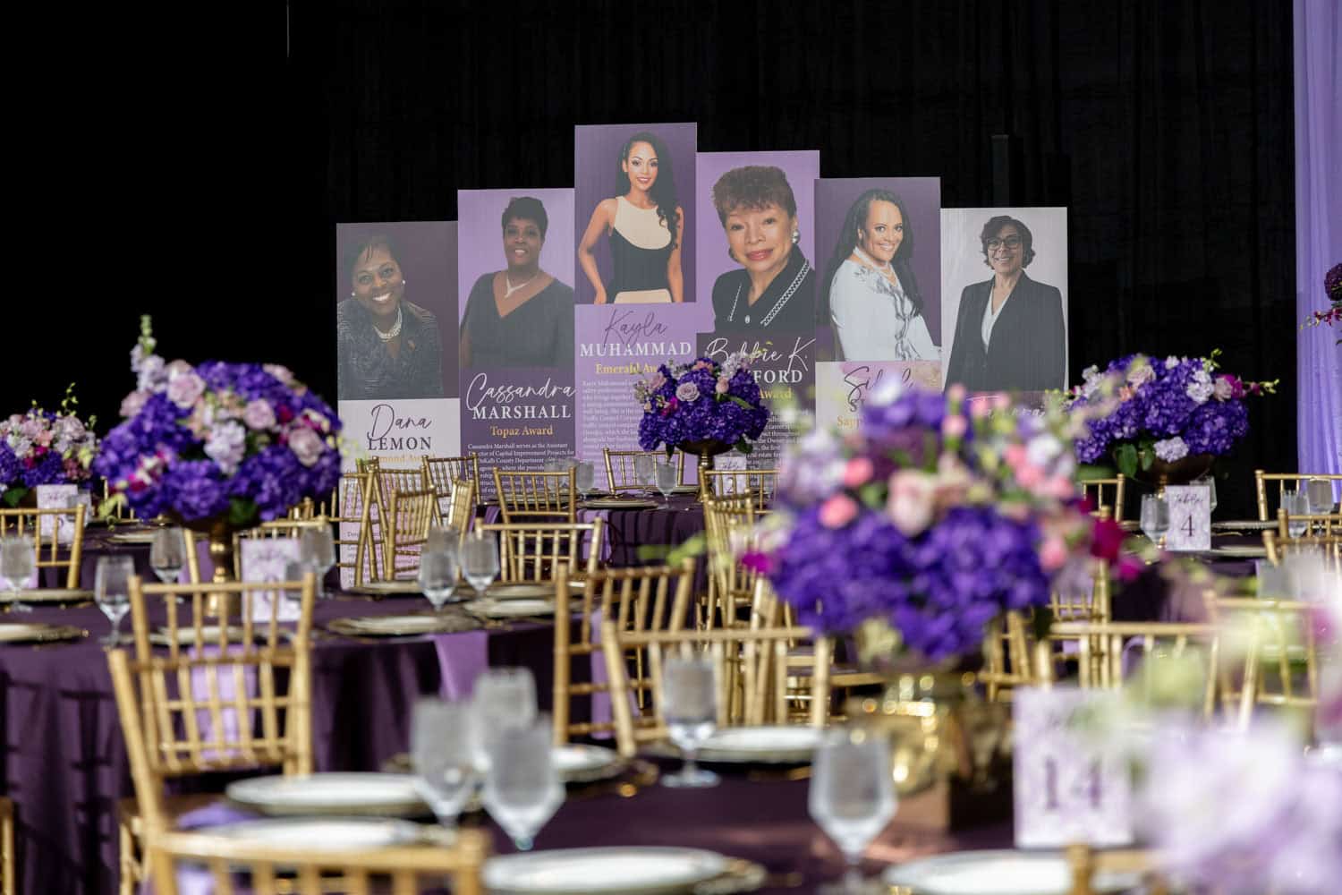 Elegant event setup with floral centerpieces and speaker portraits on stage.