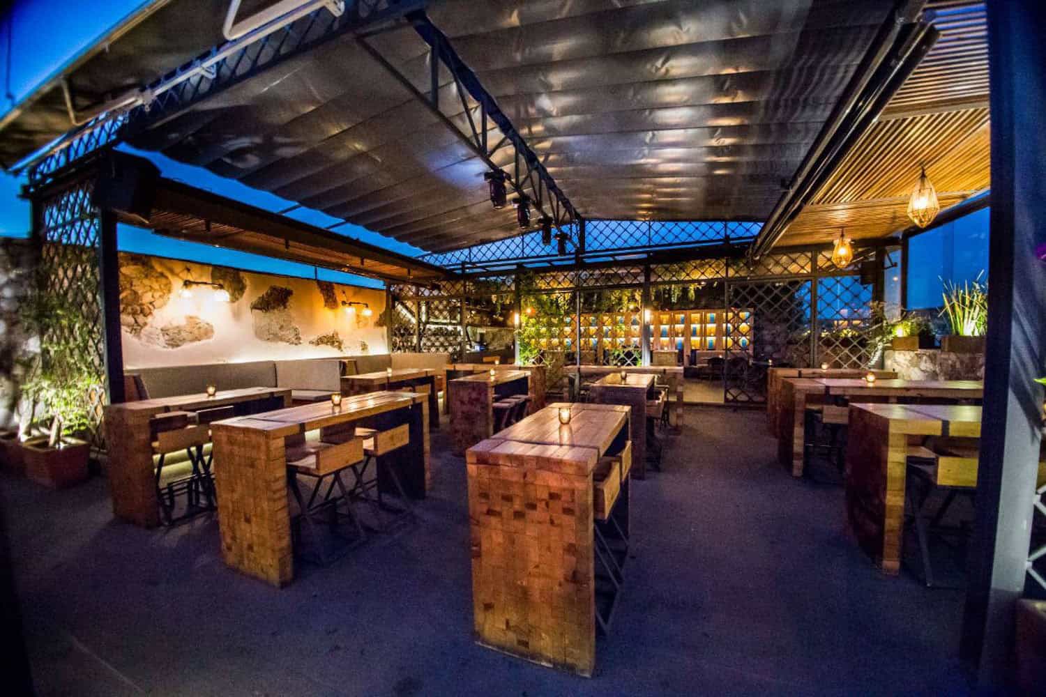 Outdoor dining space with wooden tables and ambient lighting.