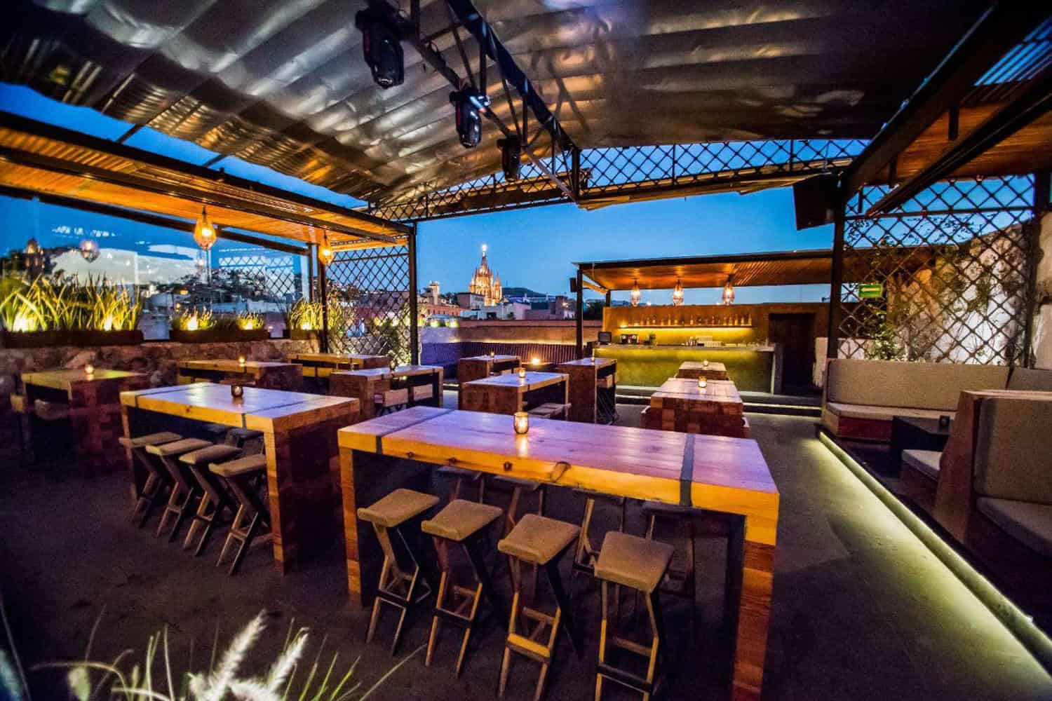 Rooftop lounge with city skyline view, modern furniture, and ambient lighting at night.