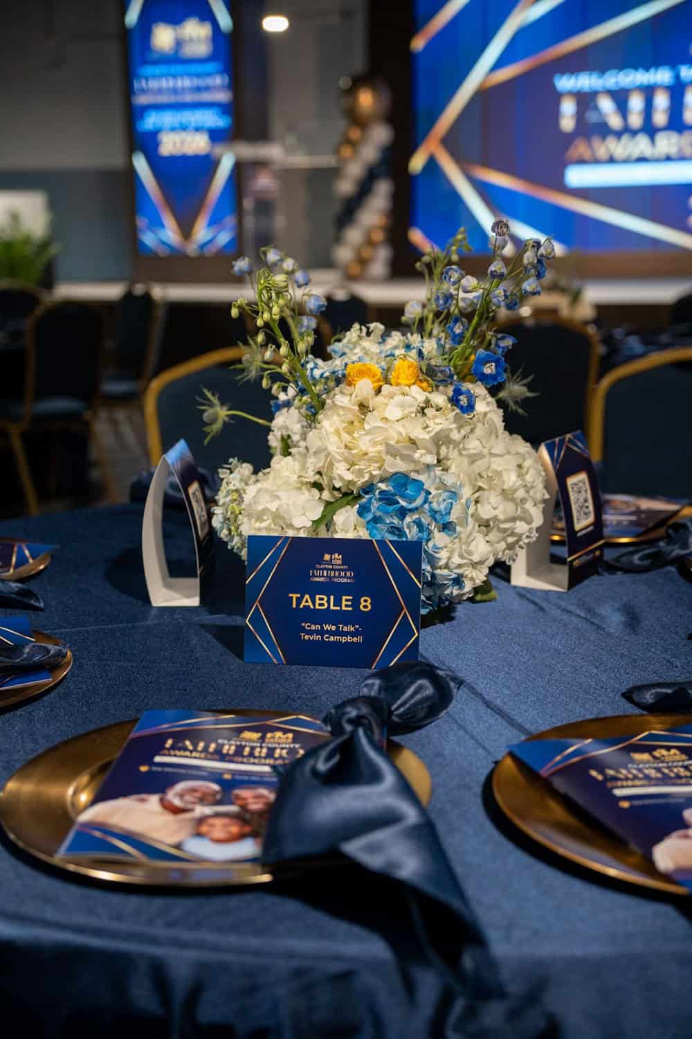 Decorated banquet table with floral centerpiece and event program at awards ceremony.