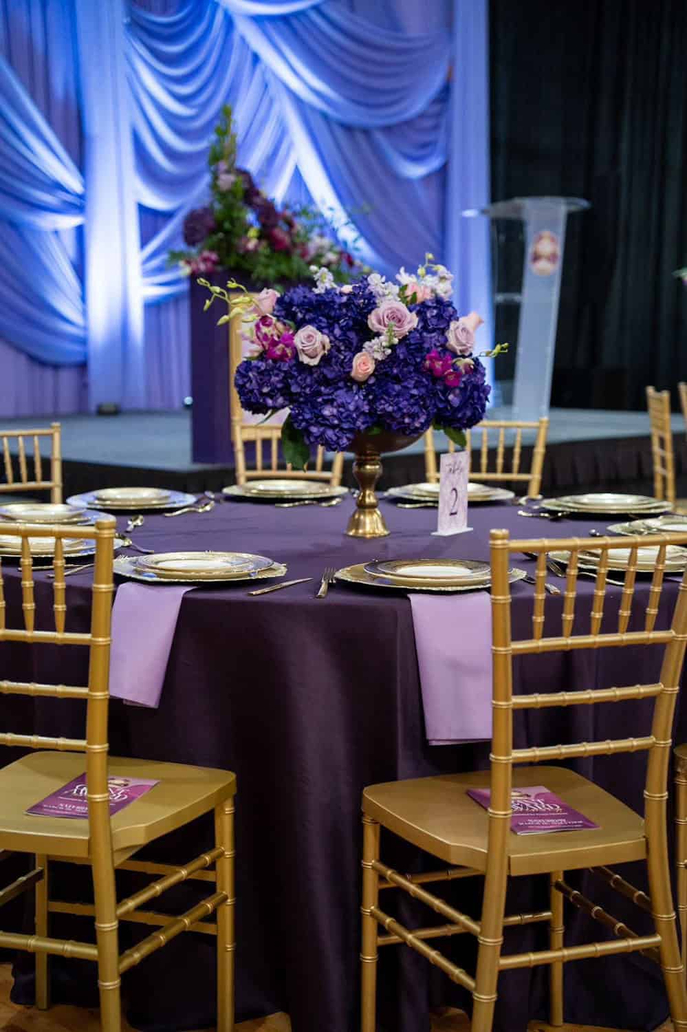 Beautifully decorated event table with purple and gold accents and floral centerpiece.