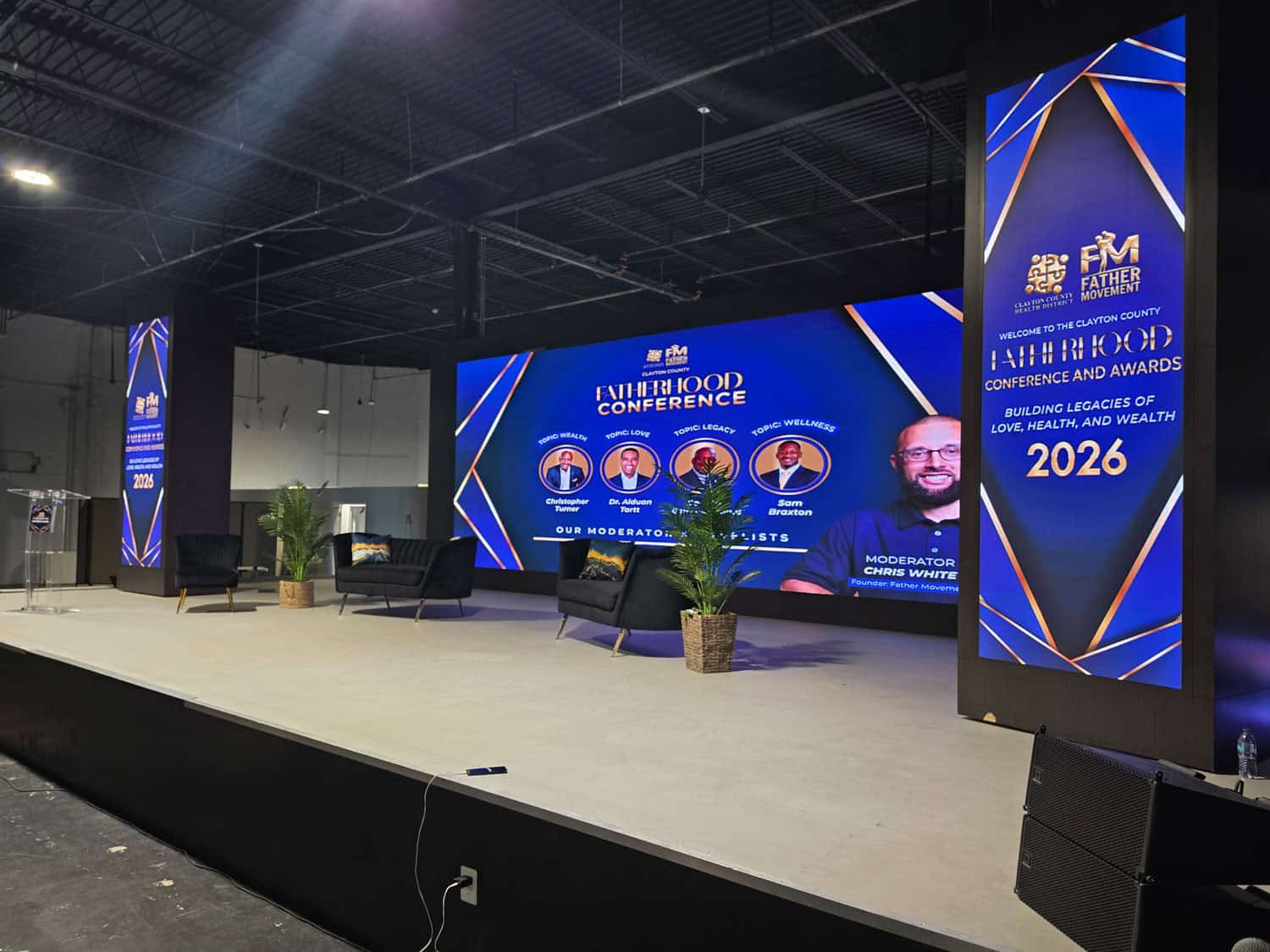 Large conference stage with digital screens displaying event details and speakers.