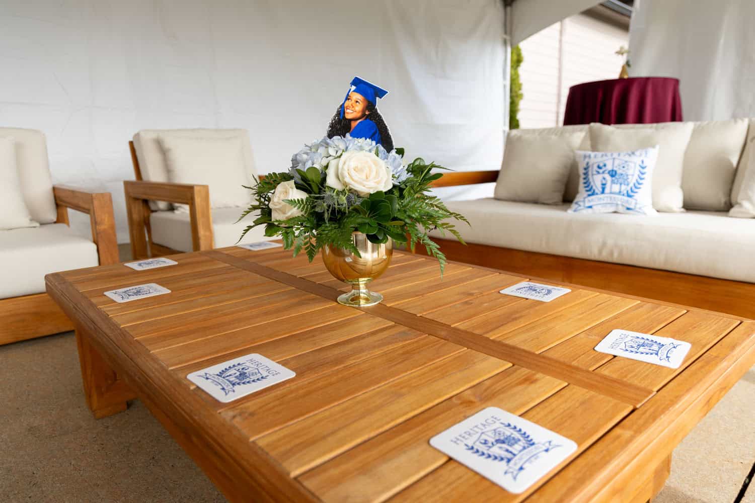 Graduation cap and diploma on a table with floral centerpiece in a tent.